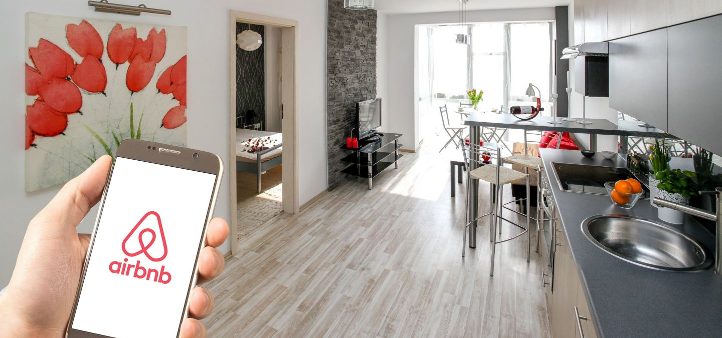 Jemand hält ein Smartphone in der Hand, auf der die airbnb App geöffnet ist.